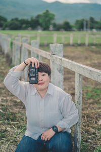 Portrait of young woman photographing at farm