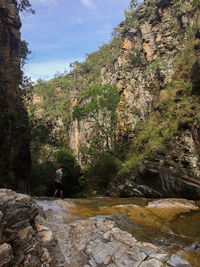 Rear view of man walking on rock by mountain