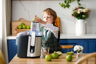 Cute schoolboy makes fresh apple juice for breakfast. vitamins and healthy nutrition for schoolers