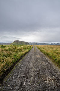 Road amidst field against sky