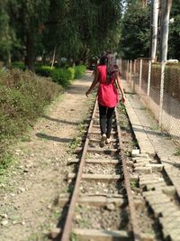 Rear view of woman walking on railroad track