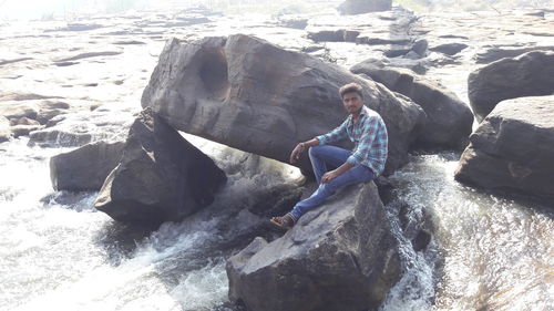 Man sitting on rock at sea shore