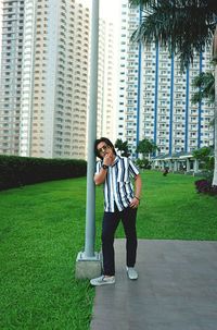 Portrait of man standing in park against building in city