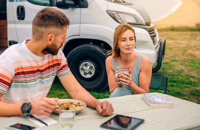 Man looking to pensive woman holding cup outdoors