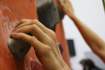 Cropped hands of woman climbing on wall