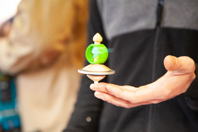 Midsection of man holding spinning top on finger