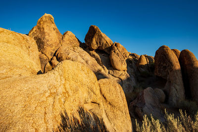 Low angle view of rocks against clear blue sky in extreme desert landscape