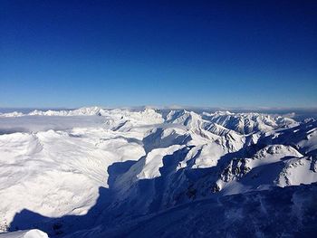 Scenic view of snowcapped mountains against blue sky