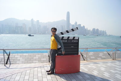 Portrait of man standing by film slate against railing in city