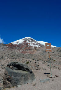 Road sign on mountain against blue sky