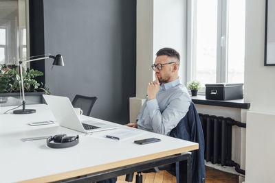 Male professional with hand on chin contemplating in office