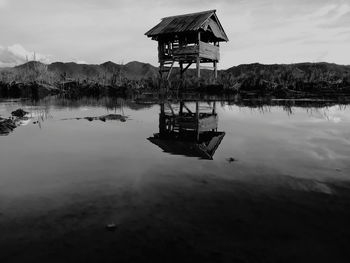 Reflection of lifeguard hut in lake against sky