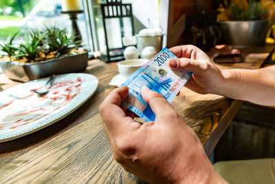 Close-up of hands holding banknote at restaurant
