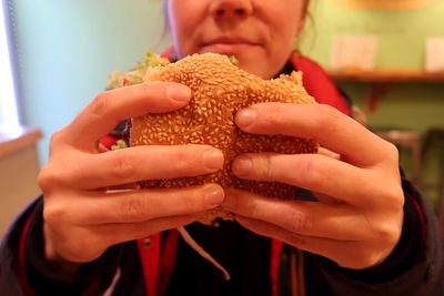 Midsection of woman holding burger at restaurant