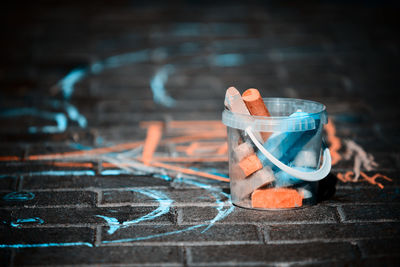 Close-up of chalks in bucket on footpath