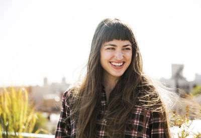 Cheerful woman looking away while standing at yard against clear sky