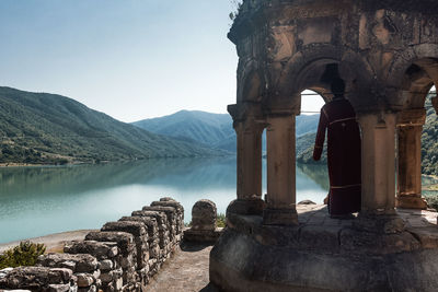 Man standing in gazebo against lake