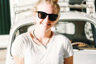 Portrait of smiling woman wearing sunglasses against car