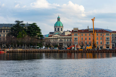 Buildings by river against sky