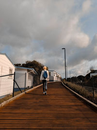 Rear view of woman walking on street against sky