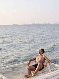 Portrait of shirtless man swimming in sea