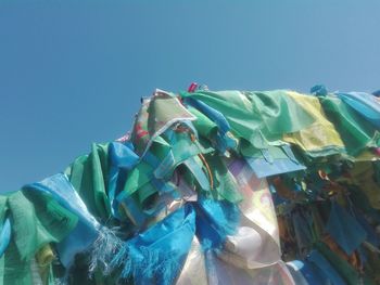 Low angle view of flags against clear blue sky