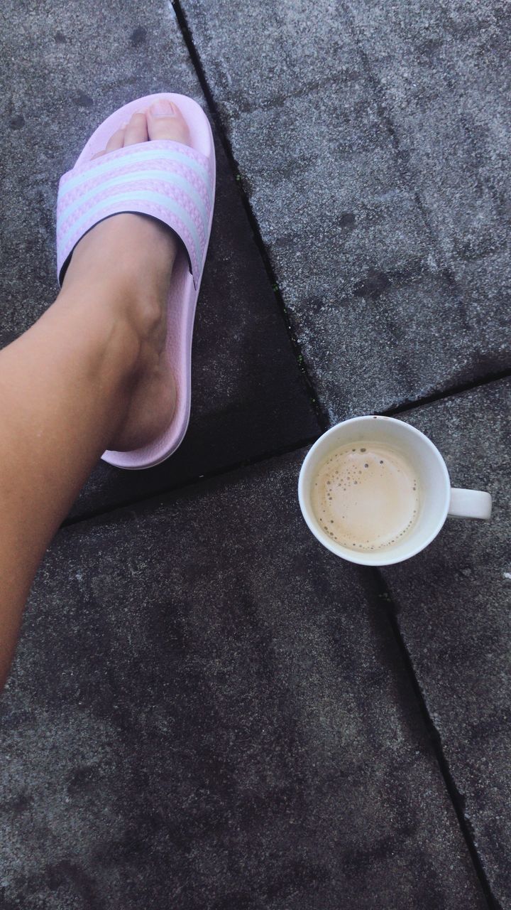 LOW SECTION OF WOMAN HOLDING COFFEE CUP WITH SPOON