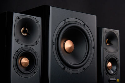 Sound audio system with two satellites and subwoofer on dark background.