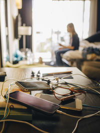 Mobile phone charging on table while girl sitting in background