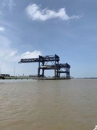 Cranes on pier over sea against sky