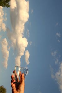 Optical illusion of person collecting clouds in glass