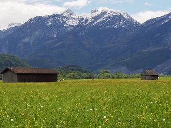 House on field by mountains against sky