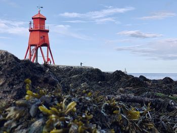 Lighthouse by sea against sky