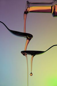 Honey pouring in spoons against colored background