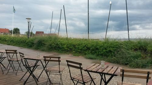 Chairs and table by grass against sky