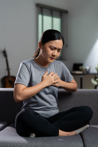 Young woman sitting on sofa at home