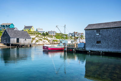 Boats moored in canal by buildings against sky