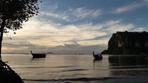 Silhouette boats in sea against sky during sunset