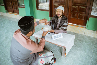 Young man helping with rice bag at mosque