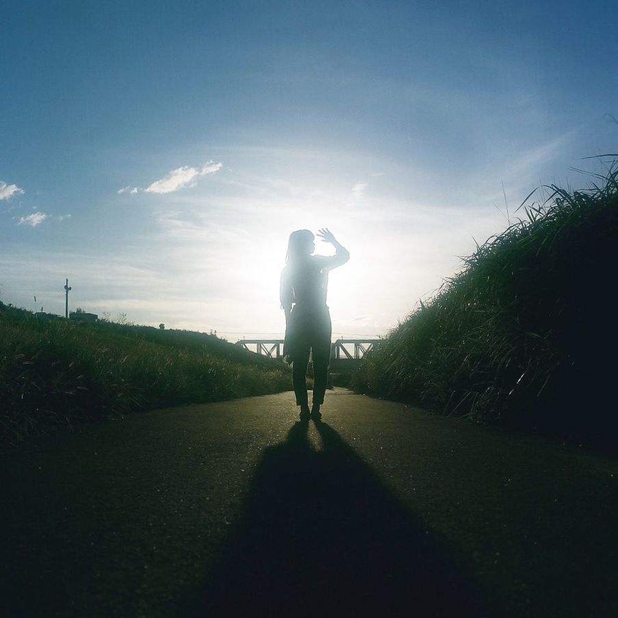 REAR VIEW OF SILHOUETTE MAN ON STREET AGAINST SKY