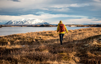 Woman hiking with backpack along lake in iceland