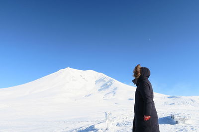 Man standing on snowcapped mountain against clear blue sky