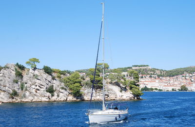 Sailboat sailing on sea against clear blue sky