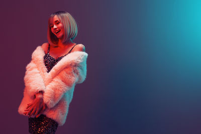 Young woman standing against blue background