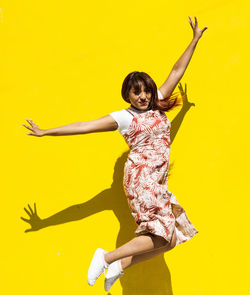 Urban women latin dancing over isolated yellow background and jumping