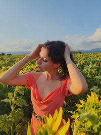 Portrait of young woman standing against sky