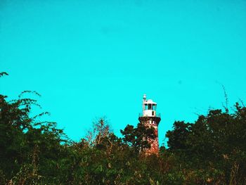 Low angle view of lighthouse by building against clear blue sky