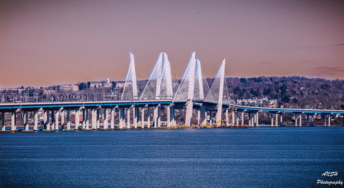 Bridge over river in city against clear sky