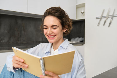 Portrait of smiling young woman reading book