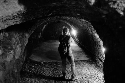 Rear view of woman standing in tunnel at night